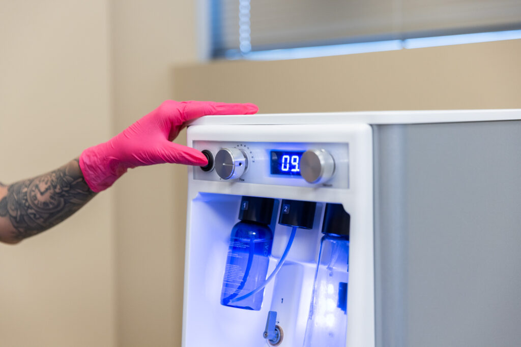 Gloved aesthetician adjusting professional skincare machine used for facials near Durant in a clinical spa setting.